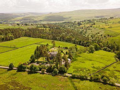 A rural landscape with fields trees and a house at Heatherbrae in Middleton-In-Teesdale