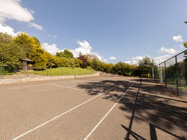 An outdoor tennis court surrounded by trees and a small wooden shed at Heatherbrae in Middleton-In-Teesdale