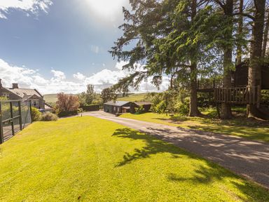 A lawn with trees a treehouse a paved driveway a house and outbuildings at Heatherbrae in Middleton-In-Teesdale
