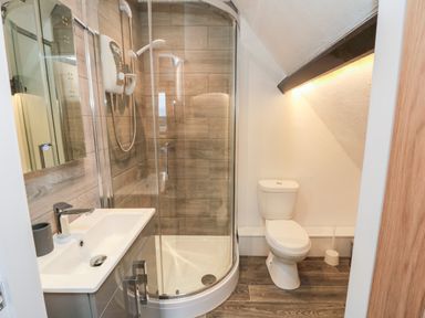 A bathroom with a corner shower, a sink with mirror, and a toilet at 4 Maypole Green in Fylingthorpe