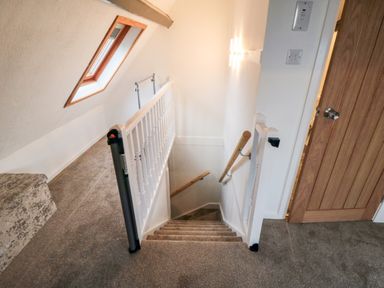 A carpeted stairway with white banisters and a wooden handrail next to a wooden door and a window at 4 Maypole Green in Fylingthorpe
