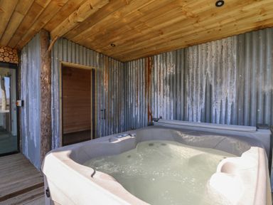 An outdoor hot tub beside a wooden ceiling and corrugated metal walls at Bryn Hafod in Llandrindod Wells
