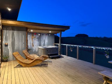 An outdoor area with a hot tub and wooden chairs at Bryn Hafod in Llandrindod Wells