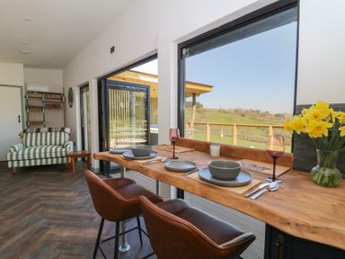 A dining area with a wooden counter and two chairs overlooking a grassy landscape at Llety Cariad in Llandrindod Wells