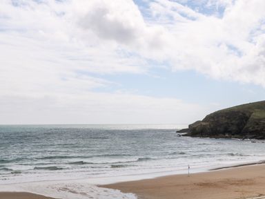 A beach with waves rolling in and a rocky cliff to the side at Sandy Cove in Praa Sands