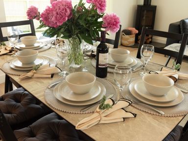 A dining table set with plates and flowers at Sandy Cove in Praa Sands