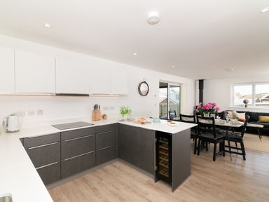 A kitchen with modern appliances and dining area at Sandy Cove in Praa Sands