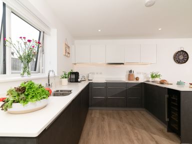 A kitchen with a sink, cabinets, and vegetables at Sandy Cove in Praa Sands