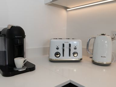 A kitchen with a Nespresso machine, kettle, toaster, and coffee cup at Sandy Cove in Praa Sands