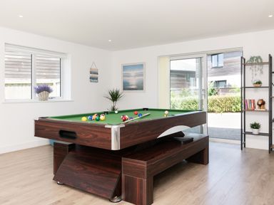 A game room with a pool table and books on a shelf at Sandy Cove in Praa Sands