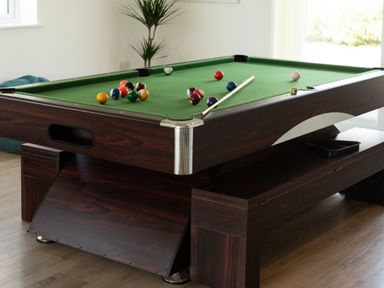A pool table with billiard balls and a cue stick at Sandy Cove in Praa Sands