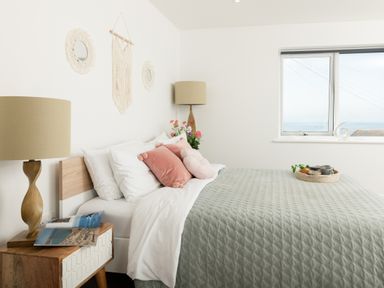 A bedroom with a bed and nightstand at Sandy Cove in Praa Sands