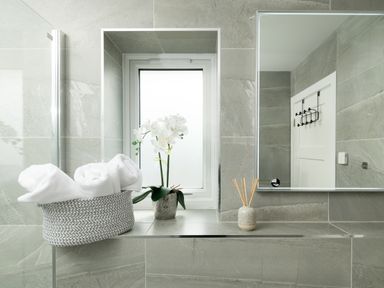 A bathroom with towels and an orchid on a shelf at Sandy Cove in Praa Sands
