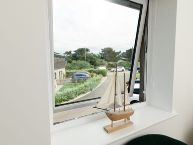A living room with a sailboat on a windowsill at Sandy Cove in Praa Sands