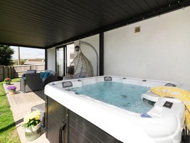 An outdoor area with a hot tub and seating at Sandy Cove in Praa Sands