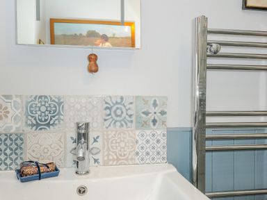A bathroom sink with patterned tile backsplash a soap dish with soap a chrome faucet and a chrome towel radiator at Lillemor in South Tawton near Whiddon Down