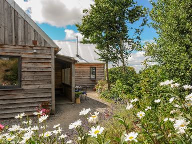 A wooden house with a gravel path and white flowers in the garden at Lillemor South Tawton near Whiddon Down