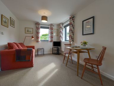 A living room with a red sofa two chairs a small wooden table and a television at Lillemor South Tawton near Whiddon Down