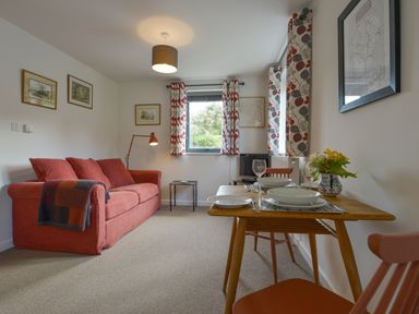 A sitting area with a red sofa and dining table set with plates and glasses at Lillemor in South Tawton near Whiddon Down