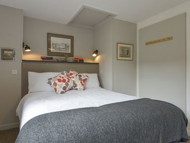 A bedroom with a double bed white linens and patterned cushions at Lillemor in South Tawton near Whiddon Down