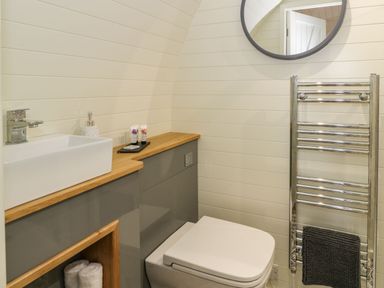 A bathroom with a toilet sink countertop and round mirror at Yr Onnen in Bontuchel near Ruthin