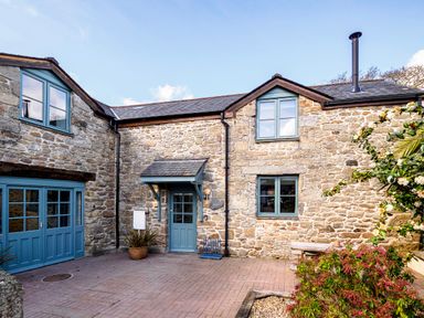 Exterior view of a stone house with blue framed windows and doors and plants in front at Trelawney in Mawnan Smith Near Falmouth