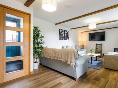 A living room with sofas a coffee table a television on the wall and wooden beams on the ceiling at Trelawney Mawnan Smith Near Falmouth