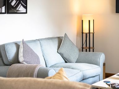 A living room with a light blue sofa striped pillows a standing lamp and a coffee table at Trelawney Mawnan Smith Near Falmouth