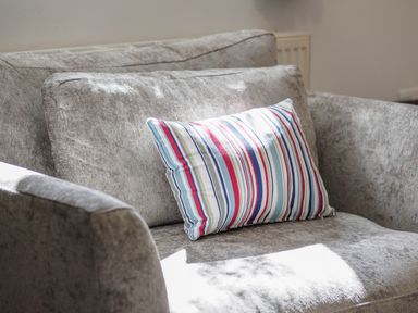 A grey fabric sofa with a striped cushion on it at Trelawney in Mawnan Smith Near Falmouth