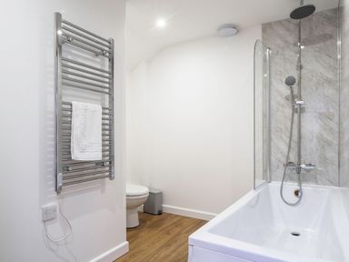 A bathroom with a bathtub and showerhead with a towel rail and toilet at Trelawney in Mawnan Smith Near Falmouth