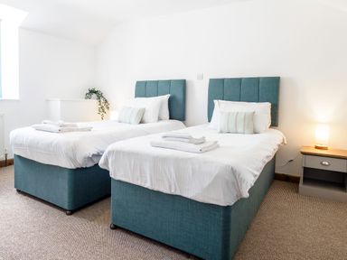 A bedroom with two single beds with blue headboards and white bedding at Trelawney Mawnan Smith Near Falmouth