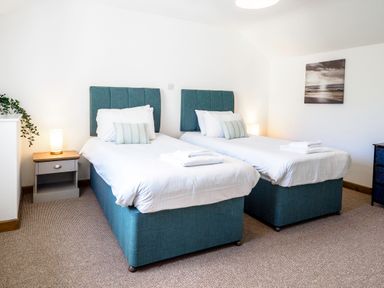 A bedroom with two single beds a nightstand with a lamp and a plant and a framed picture on the wall at Trelawney Mawnan Smith Near Falmouth