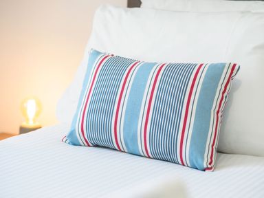 A bed with white sheets and a striped pillow with blue red and white colors at Trelawney Mawnan Smith Near Falmouth