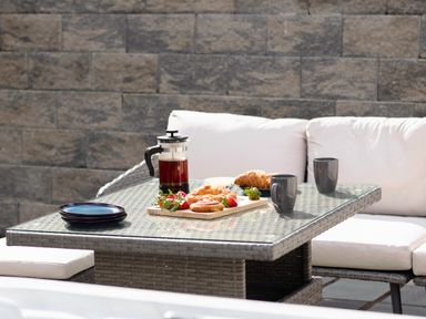 An outdoor patio table with coffee pot mugs croissants strawberries and plates with cushioned seating at Trelawney in Mawnan Smith Near Falmouth
