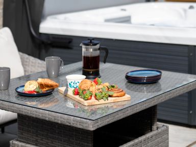 A glass table with croissants strawberries a coffee press and cups on a patio at Trelawney Mawnan Smith Near Falmouth