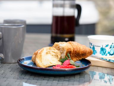 A plate with a croissant and sliced strawberries with a mug and a coffee pot in the background at Trelawney in Mawnan Smith Near Falmouth