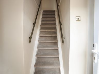 A narrow carpeted staircase with handrails on both sides at Frongoch Cottage in Red Wharf Bay near Pentraeth