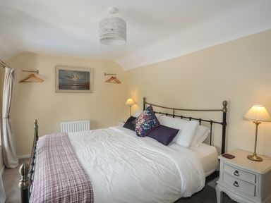 A bedroom with a double bed two bedside tables and lamps and a painting on the wall at Frongoch Cottage in Red Wharf Bay near Pentraeth