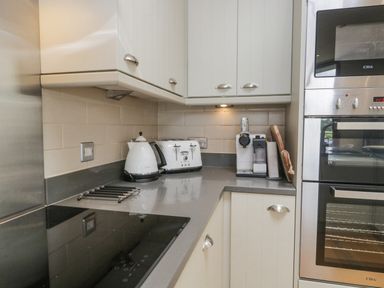A kitchen counter with a kettle, toaster, coffee machine, stove, and built-in oven at Rivendell Lodge Roger Ground near Hawkshead