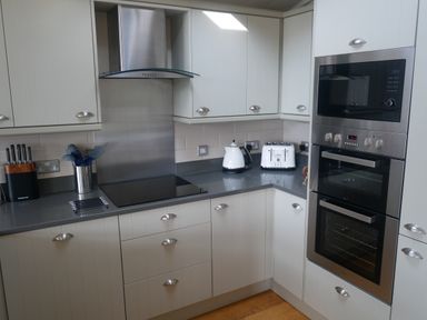 A kitchen with white cabinets a stovetop a toaster a kettle knives and built in oven and microwave at Rivendell Lodge Roger Ground near Hawkshead