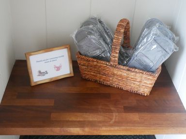 A basket with multiple pairs of slippers and a framed sign on a wooden surface at Rivendell Lodge in Roger Ground near Hawkshead