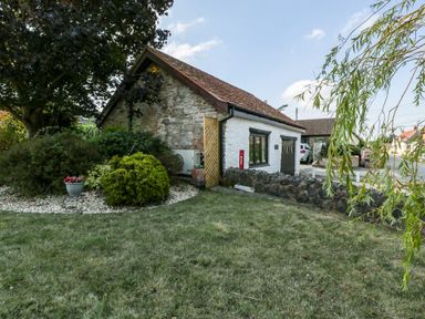 A garden with bushes and a tree next to a stone and white house at The Forge in Taunton