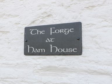 A black sign with white text on a white textured wall at The Forge in Taunton