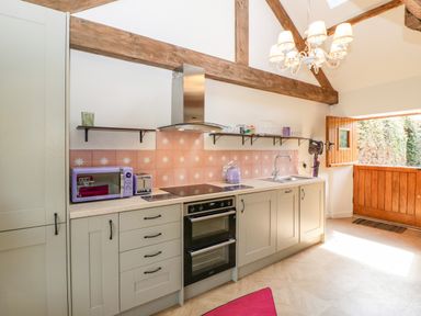 A kitchen with cabinets oven microwave toaster kettle and open wooden door at The Forge in Taunton