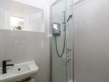 A small bathroom with a wall-mounted sink and a glass-enclosed shower at The Forge in Taunton
