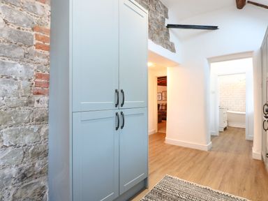 A hallway with blue cabinets wooden floor and stone and white walls at Well Cottage in Grimston