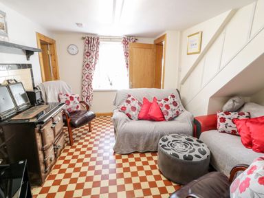 A living room with a stove two sofas armchairs and patterned cushions at Peters Farmhouse in Cookstown