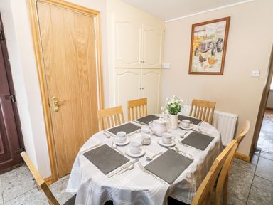 A dining table set for six with cups, saucers, teapot, and flower vase in a kitchen at Peters Farmhouse Cookstown