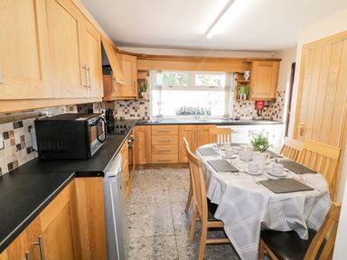 A kitchen with wooden cabinets black countertops a table with a checkered tablecloth and place settings at Peters Farmhouse in Cookstown