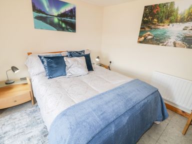 A bedroom with a bed with pillows and blankets and two nightstands with lamps at Peters Farmhouse in Cookstown